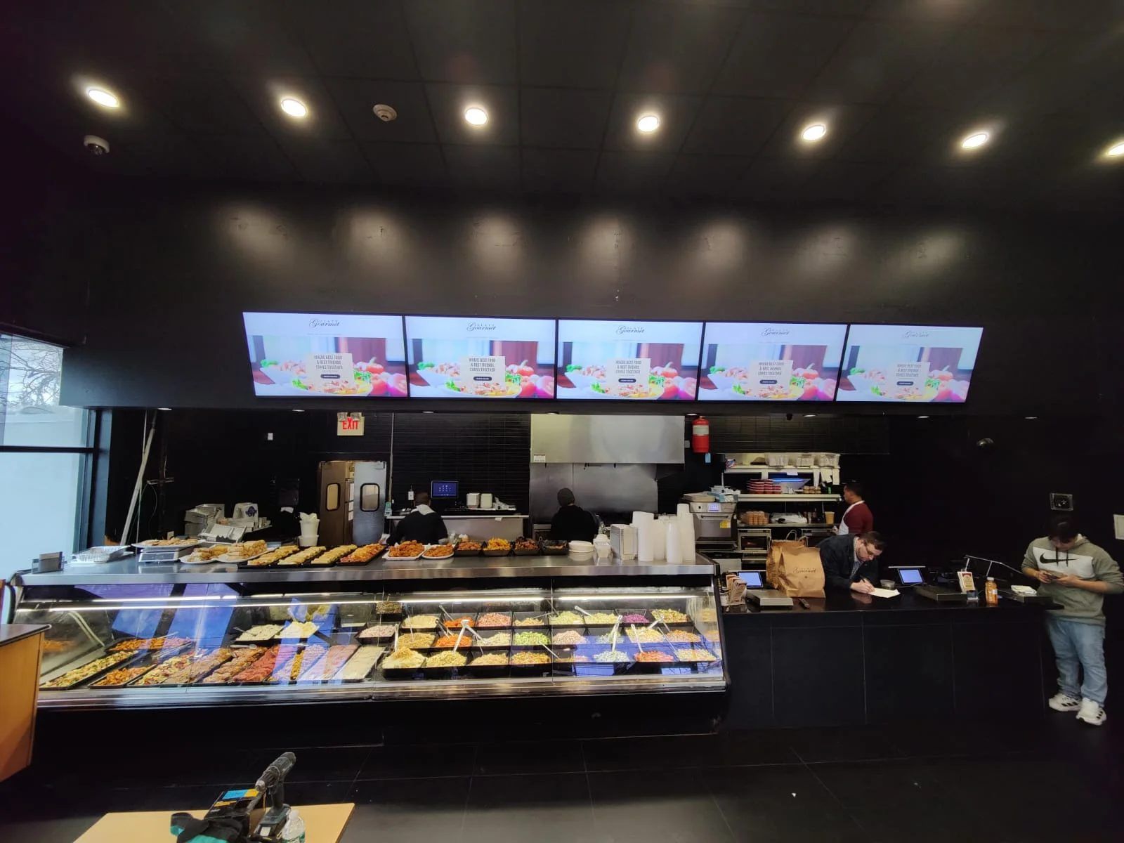 CrownTV install: row of menu board displays above a deli counter