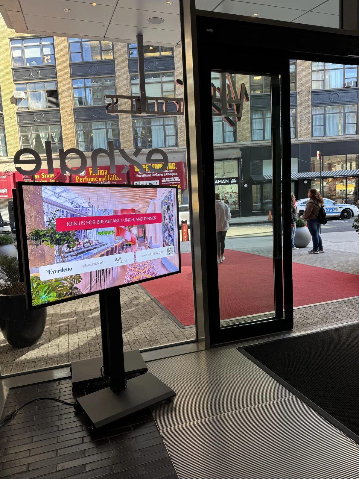 Samsung 55 inch commercial display on a black floor stand at a Manhattan store entrance