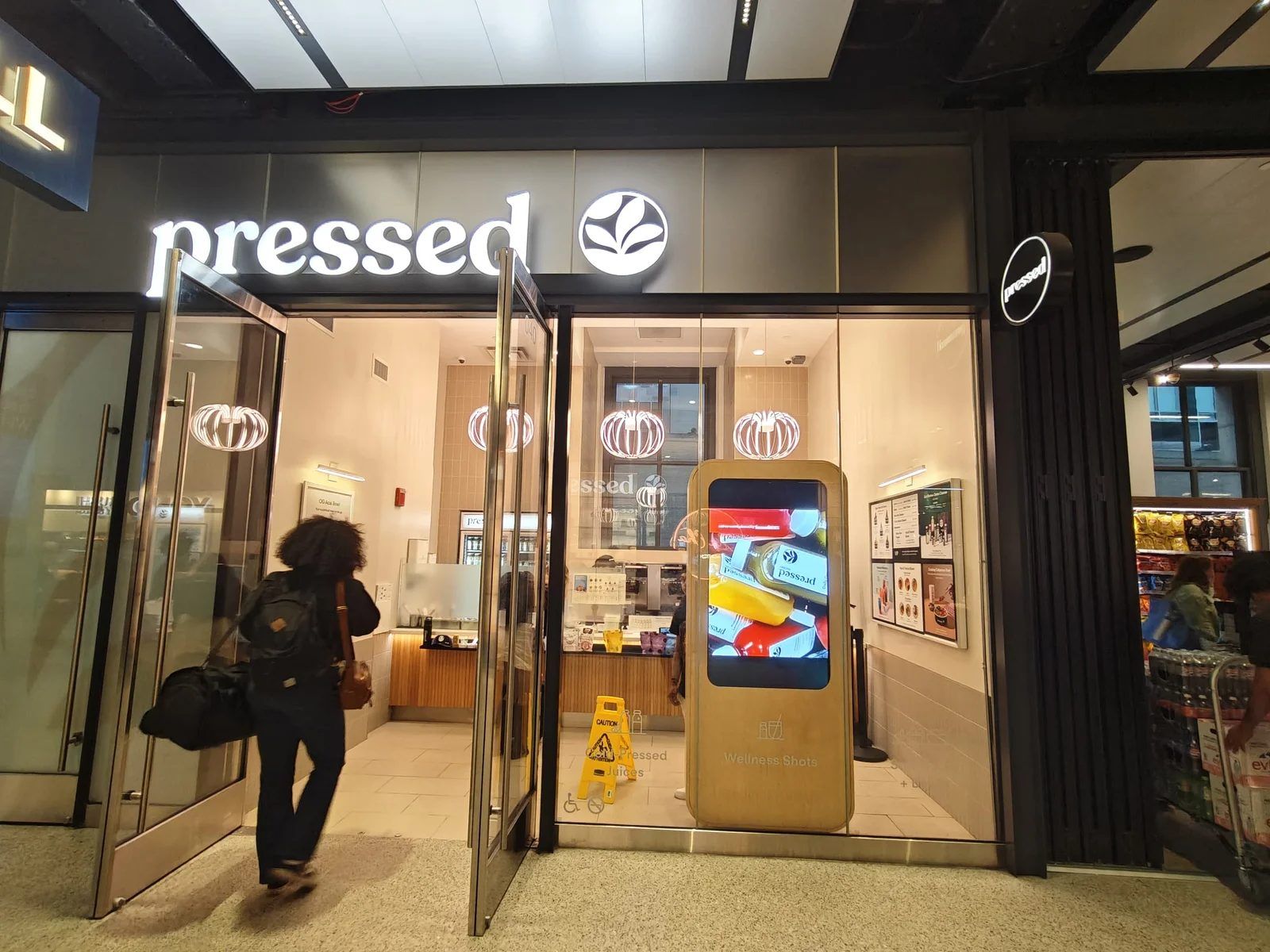 CrownTV install: portrait display in a branded floor kiosk at a Pressed storefront